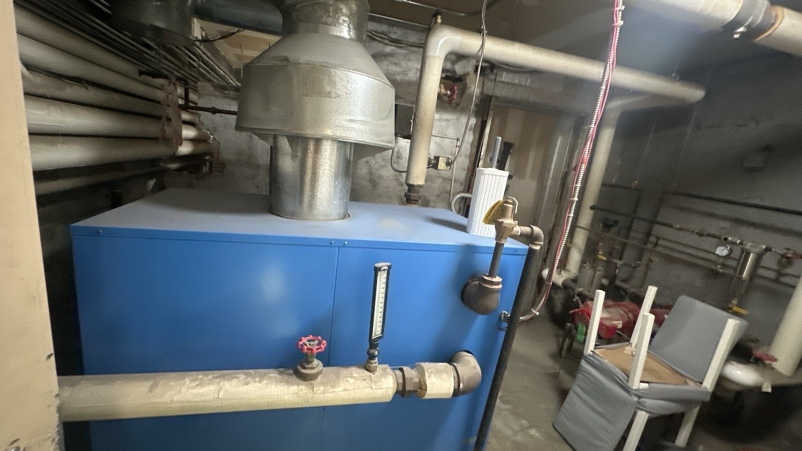 Gas-fired hydronic boiler with insulated heating pipes in a commercial building mechanical room