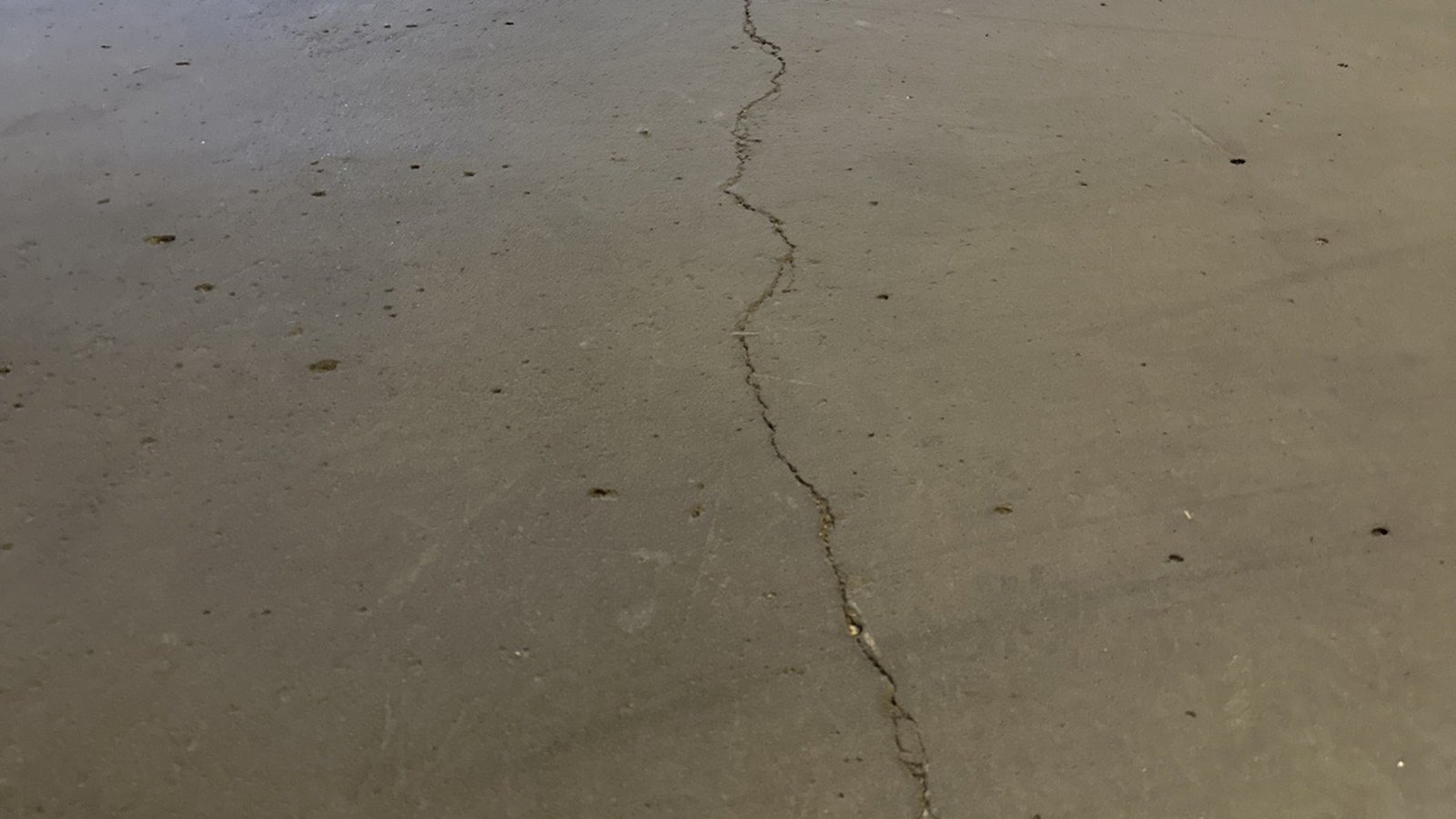 Long crack running across a concrete slab-on-grade floor in a commercial warehouse